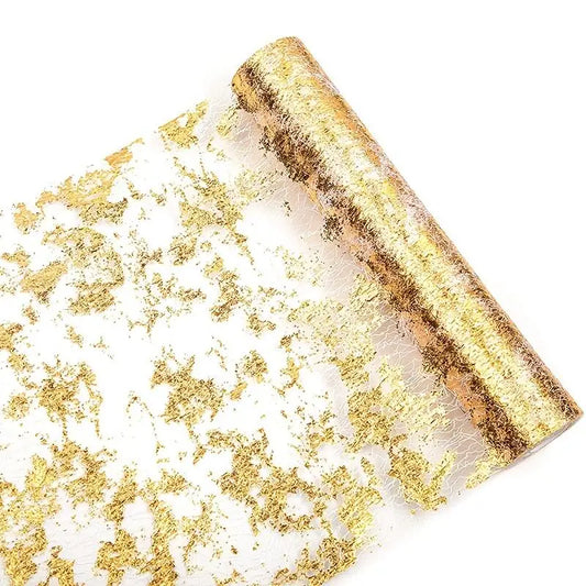 A roll of decorative mesh fabric with a gold leaf pattern scattered across a transparent background, creating an elegant, shimmering effect.