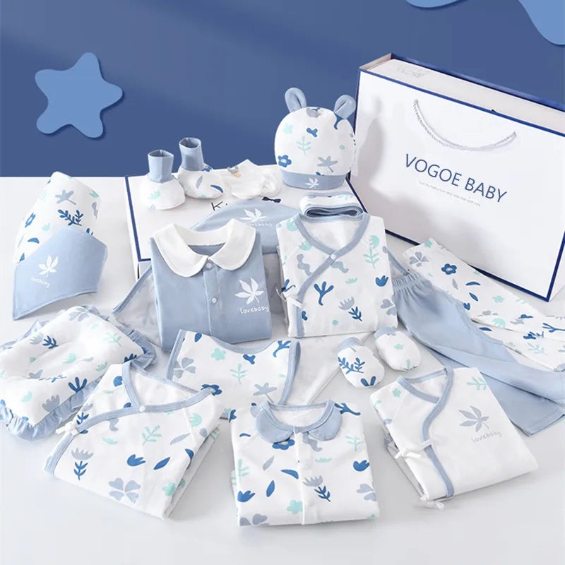 Assorted baby clothing set in blue and white with floral patterns, including pajamas, mittens, hats, and more. A gift box labeled "VOGOE BABY" is in the background.