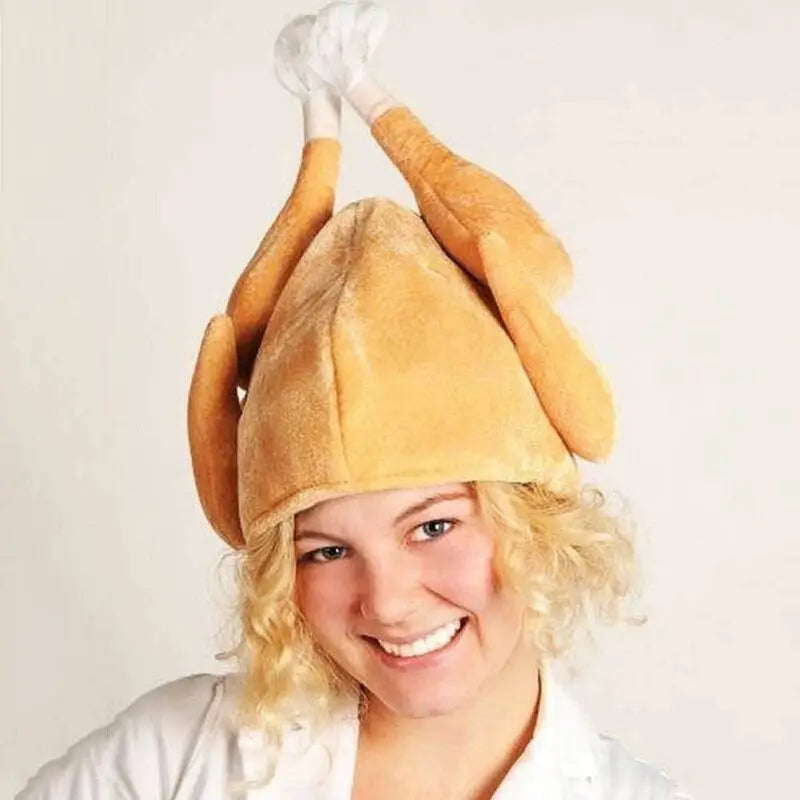 Person smiling while wearing a humorous hat shaped like a roasted turkey, including drumsticks. The background is plain white, highlighting the playful headwear.