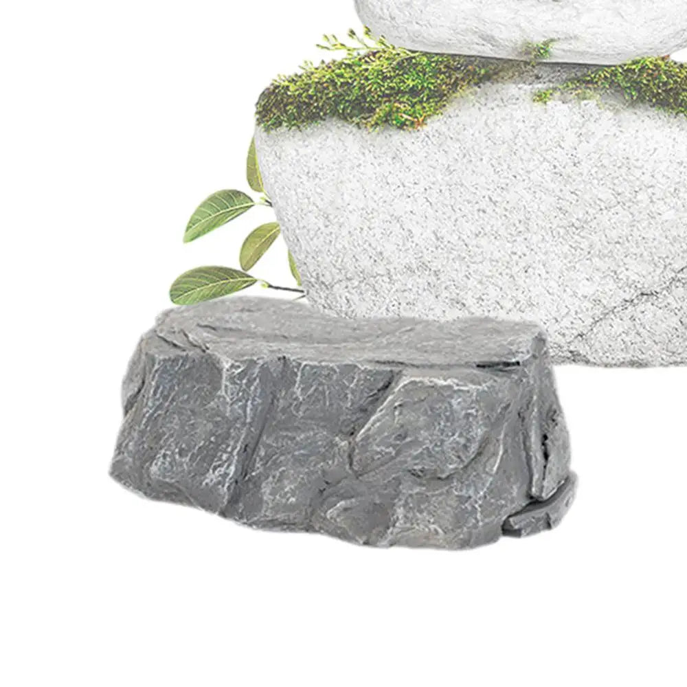 Gray rock formations with green leaves and moss growing on top. The stones are textured with a natural appearance, creating a serene, nature-inspired setting.