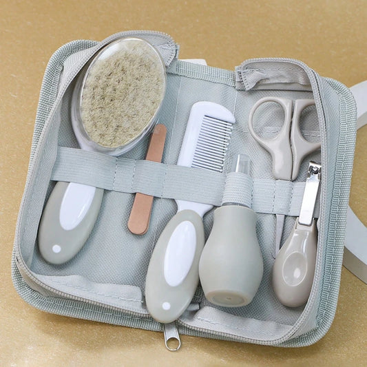 Baby grooming kit with a soft brush, comb, nail file, nasal aspirator, scissors, and nail clippers, neatly organized in a gray fabric case on a tan surface.