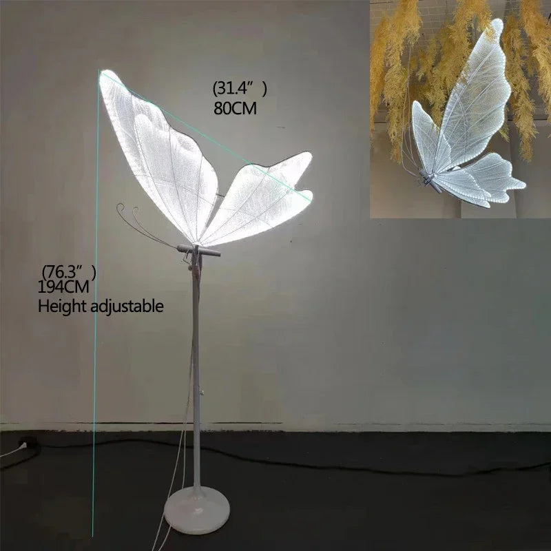 Tall floor lamp with a butterfly wing design, standing at 76.3 inches (194cm) adjustable height. The wingspan measures 31.4 inches (80cm), emitting a soft, white light.