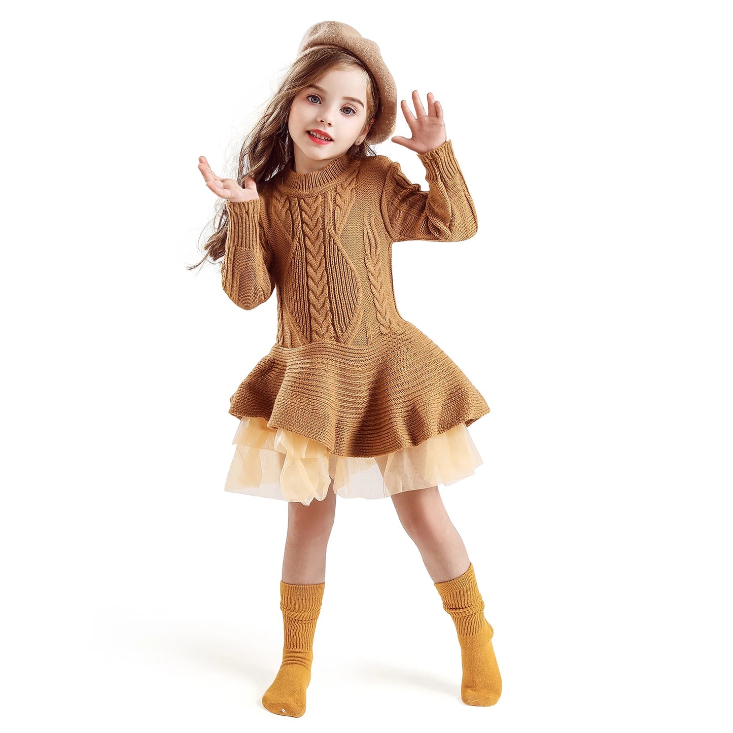 Young girl in a brown knitted dress with a flared skirt and tulle, matching beret, and yellow socks, playfully posing against a white background.