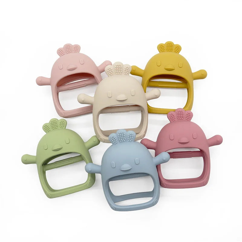 Six colorful chicken-shaped silicone teethers with small protrusions on top are arranged in a circle. Colors include pink, beige, yellow, green, blue, and rose.
