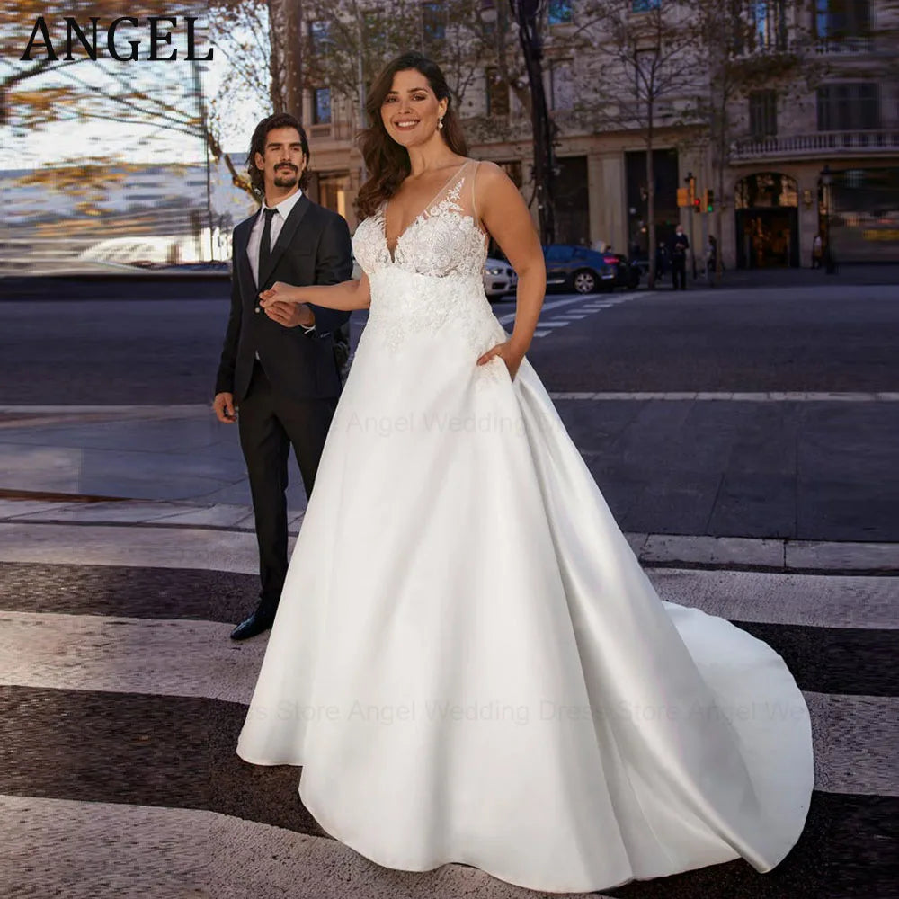 Bride in a white gown with lace bodice standing on a city street, smiling and holding hands with a man in a dark suit. Background shows urban buildings and trees.