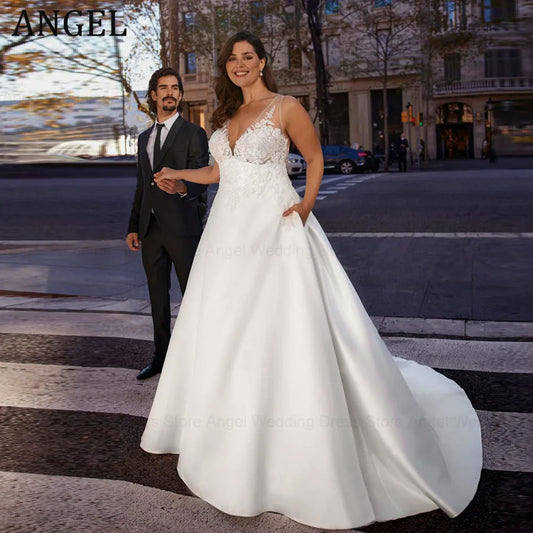 Bride in a white gown with lace bodice standing on a city street, smiling and holding hands with a man in a dark suit. Background shows urban buildings and trees.