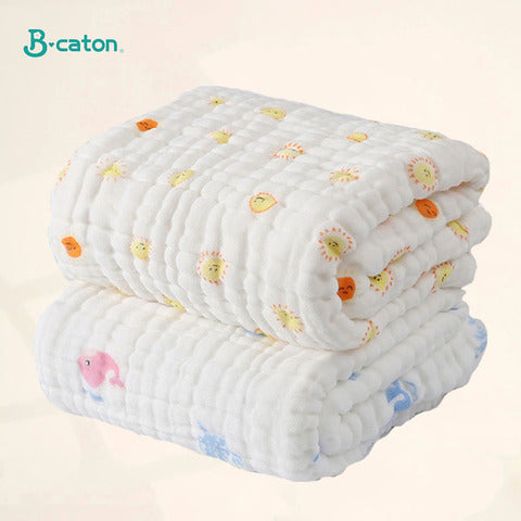 Two soft, white, quilted blankets are stacked. The top blanket features colorful sun and lion patterns, while the bottom one displays fish motifs. The logo "B-caton" is in the corner.