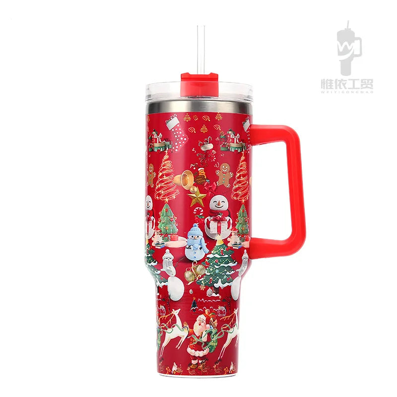 Red tumbler with festive Christmas designs featuring snowmen, trees, and Santa Claus. It has a clear lid with a straw and a large red handle on the side.