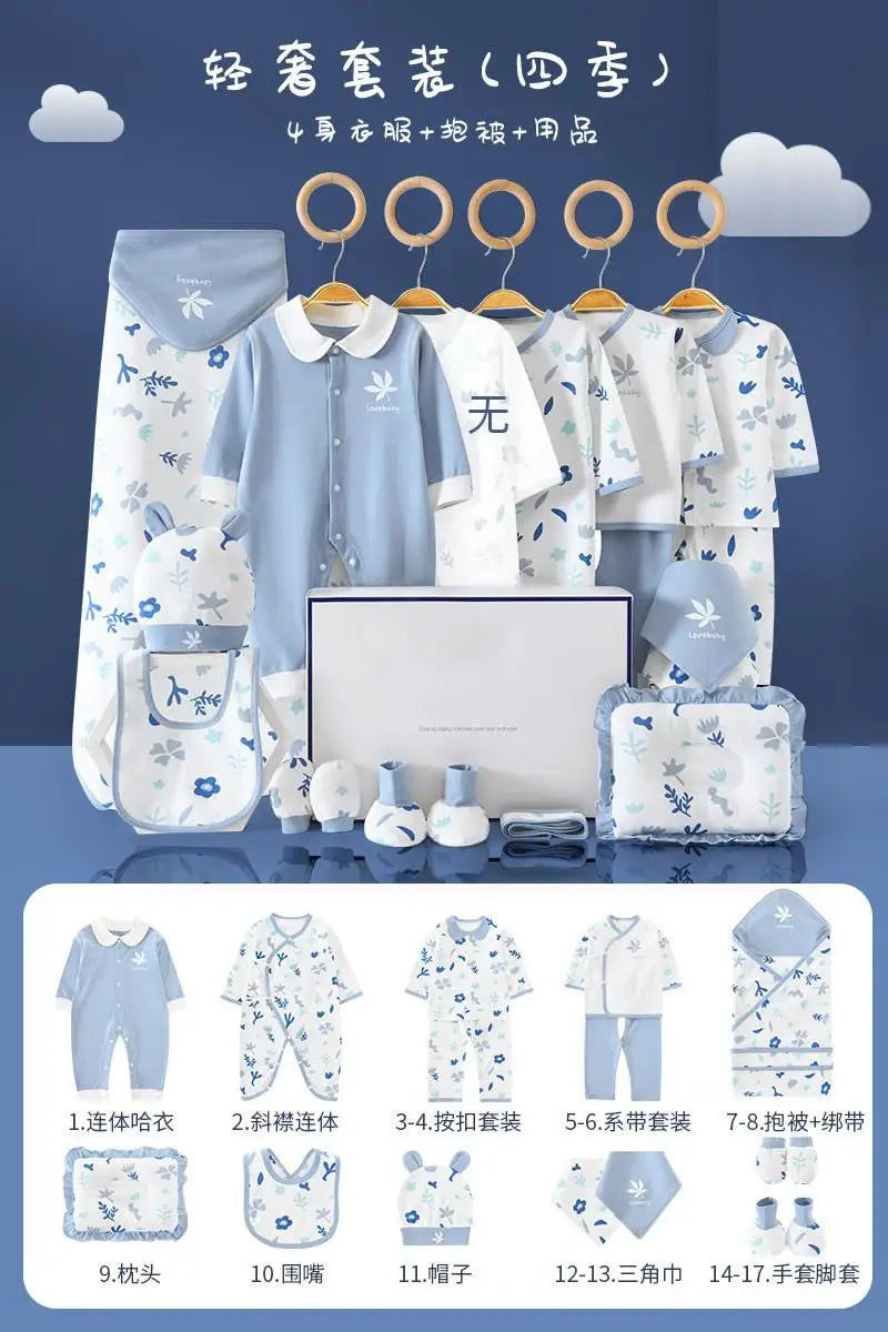 Baby clothing set in blue and white with floral patterns. Includes onesies, bibs, hats, booties, pillow, mittens, and a blanket. Items displayed on hangers and neatly arranged.