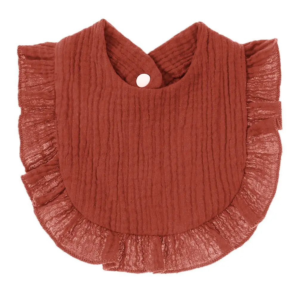 Rust-colored baby bib with ruffled edges and a textured fabric pattern. Features a snap button closure at the top center. Ideal for keeping clothes clean.