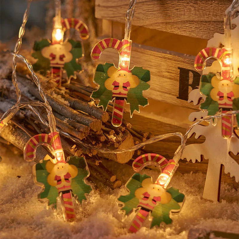 Festive string lights featuring Santa figures with candy canes, surrounded by snow and logs, creating a cozy holiday atmosphere.