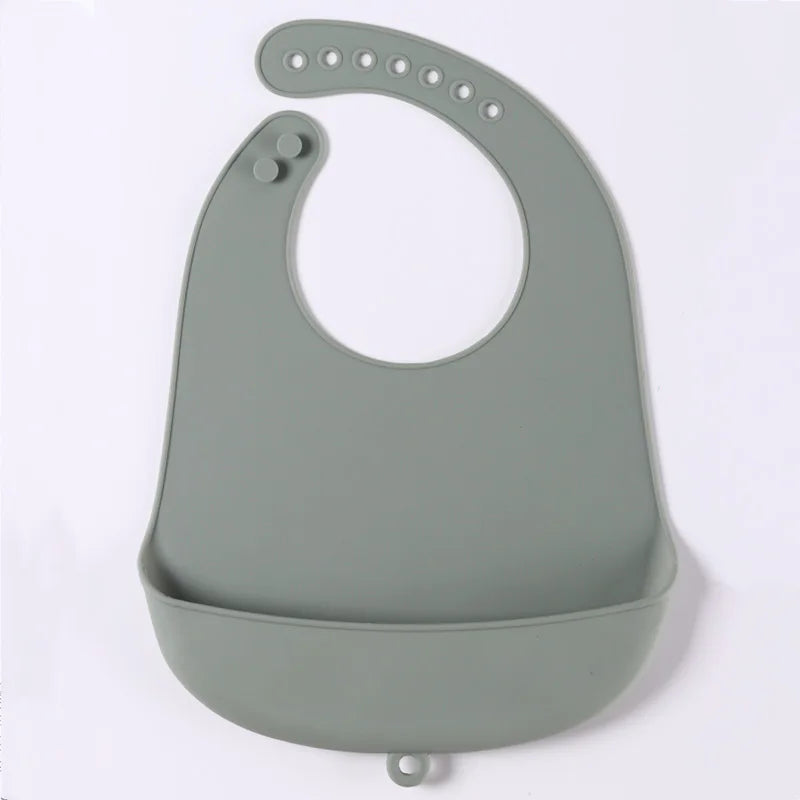 A grey silicone baby bib with adjustable neck straps and a deep pocket for catching food spills, laid flat against a white background.