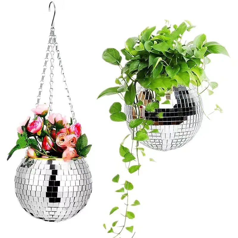 Two hanging disco ball planters: one with vibrant pink flowers, the other with cascading green vines. Both reflect light, creating a shiny, decorative effect.