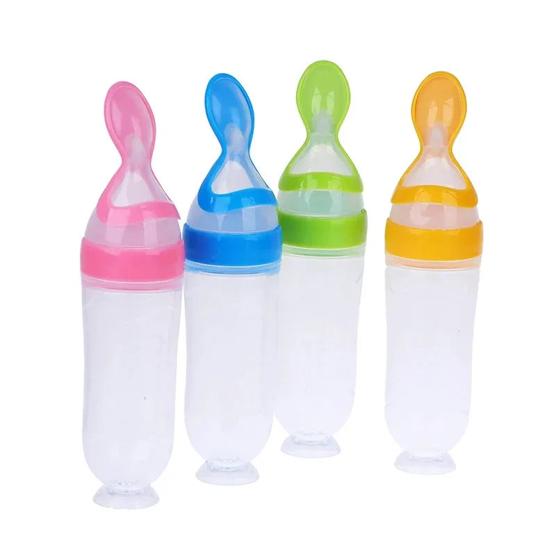 Four baby food dispensing bottles with spoon tips in pink, blue, green, and orange caps, standing upright against a white background.