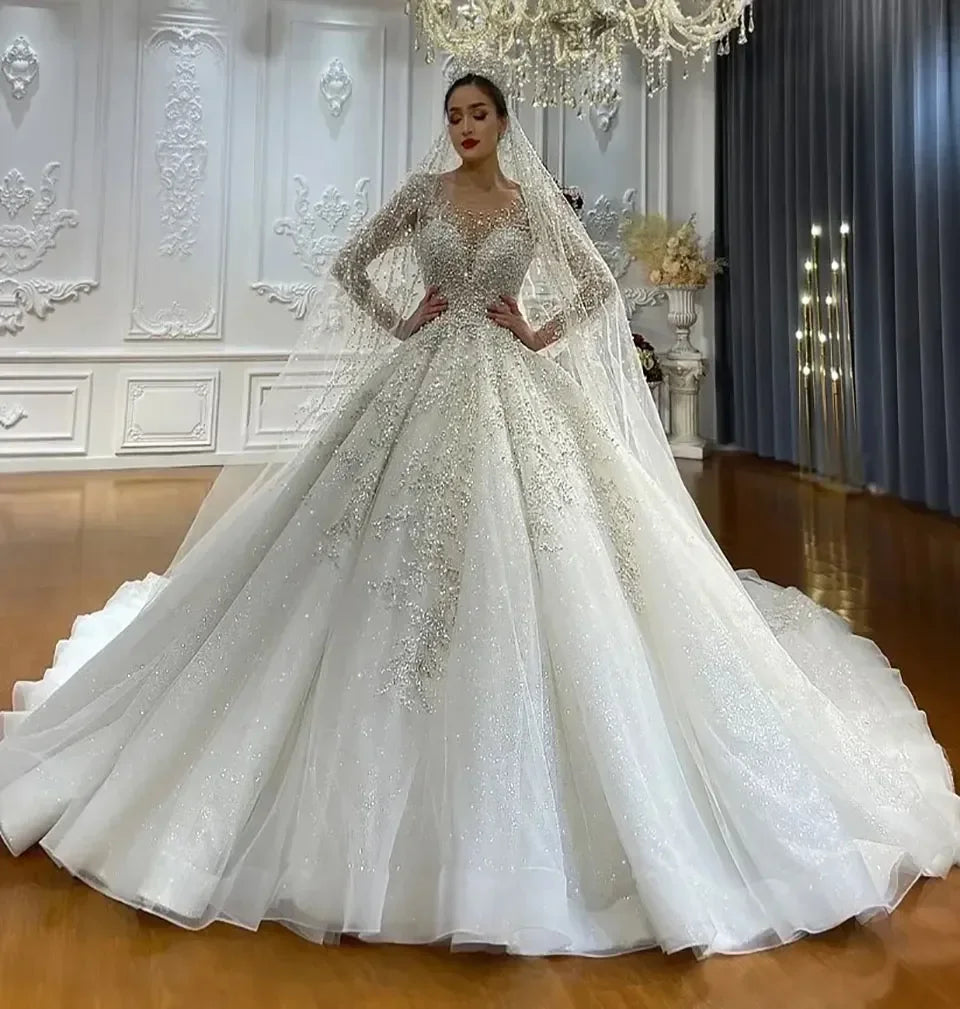 Opulent ballroom setting with a bride in an elaborate, shimmering white gown and long veil, standing confidently under an ornate chandelier, surrounded by elegant decor.