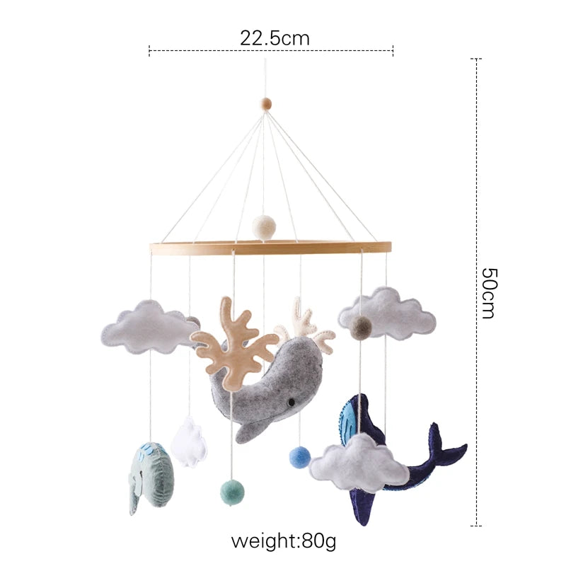 Baby mobile with felt sea creatures, including a whale and clouds, hanging on strings from a circular frame. Dimensions are 22.5cm wide and 50cm tall, weighing 80g.