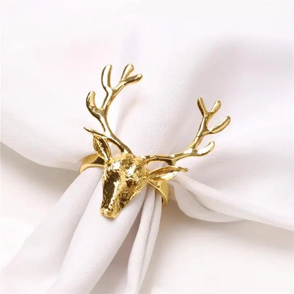 Gold deer head napkin ring with detailed antlers, elegantly securing a white napkin folded and gathered in the center.