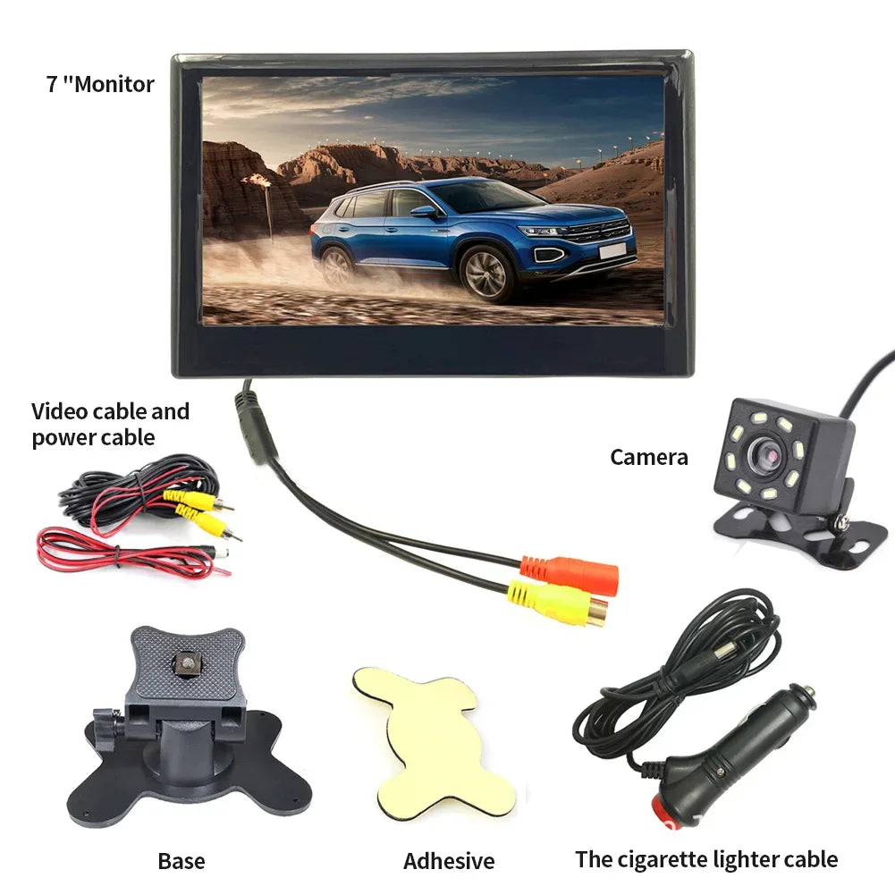 Car rearview camera kit with a 7-inch monitor displaying a blue SUV, camera, power and video cables, base, adhesive, and cigarette lighter cable laid out separately.