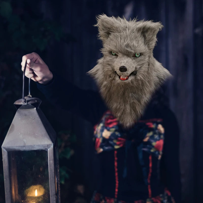 Person wearing a furry wolf mask, holding a lantern with a glowing candle inside, against a dark, blurred background.
