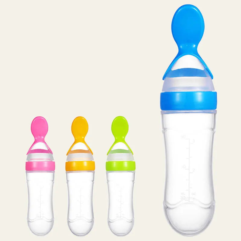 Four transparent baby food squeeze bottles with attached spoons in pink, orange, green, and blue. The bottles are graduated and vary in size, arranged against a plain background.