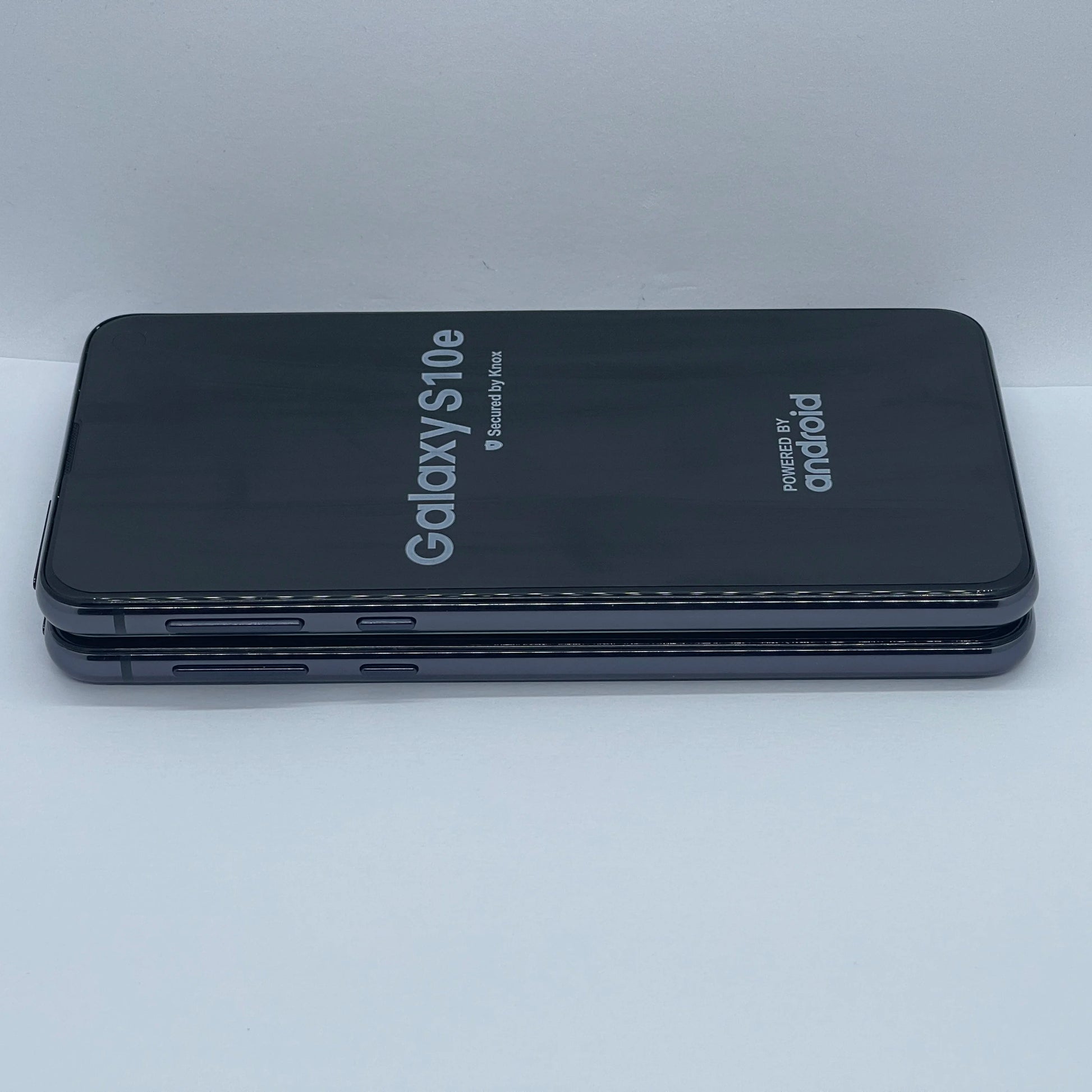 Two Samsung Galaxy S10e smartphones are stacked. The screens display "Galaxy S10e" and "Powered by Android." The phones have a sleek, dark design with visible side buttons.