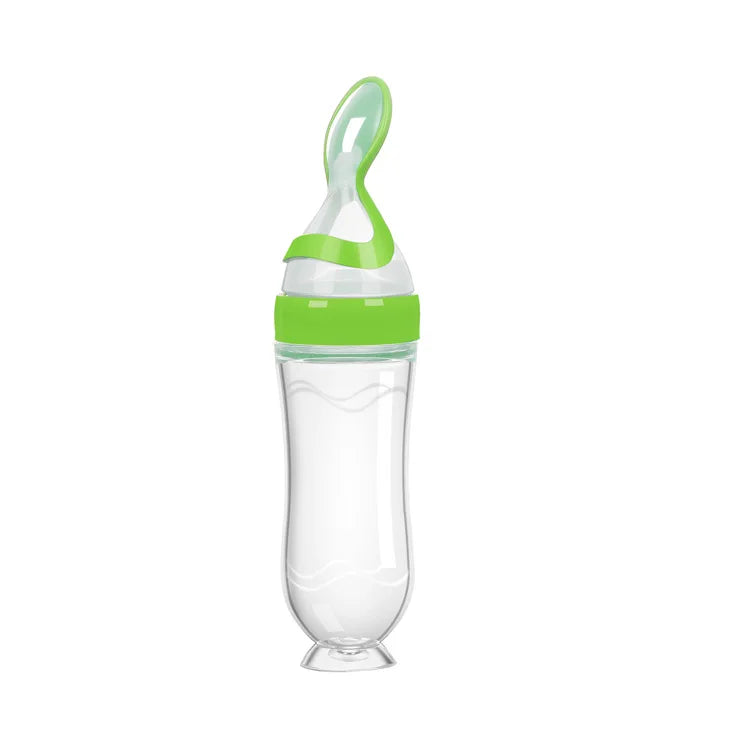Transparent baby bottle with a green lid and built-in spoon, designed for easy feeding. The curved bottle has a secure base, and the spoon is neatly integrated into the cap.