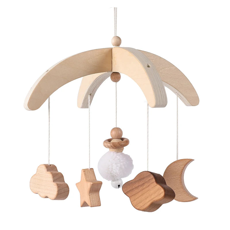 Wooden baby mobile with cloud, star, pom-pom, leaf, and crescent moon shapes hanging from an arched frame. Simple, natural design for nursery decor.