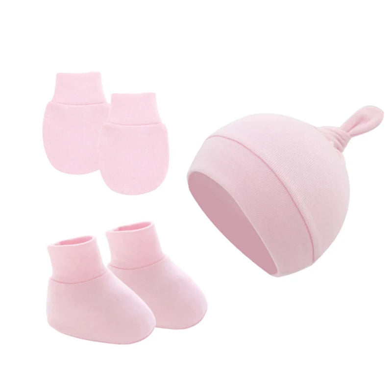 Pink baby set featuring a hat with a knot on top, a pair of booties, and mittens, all made from soft fabric for comfort. Perfect for keeping a newborn warm and cozy.