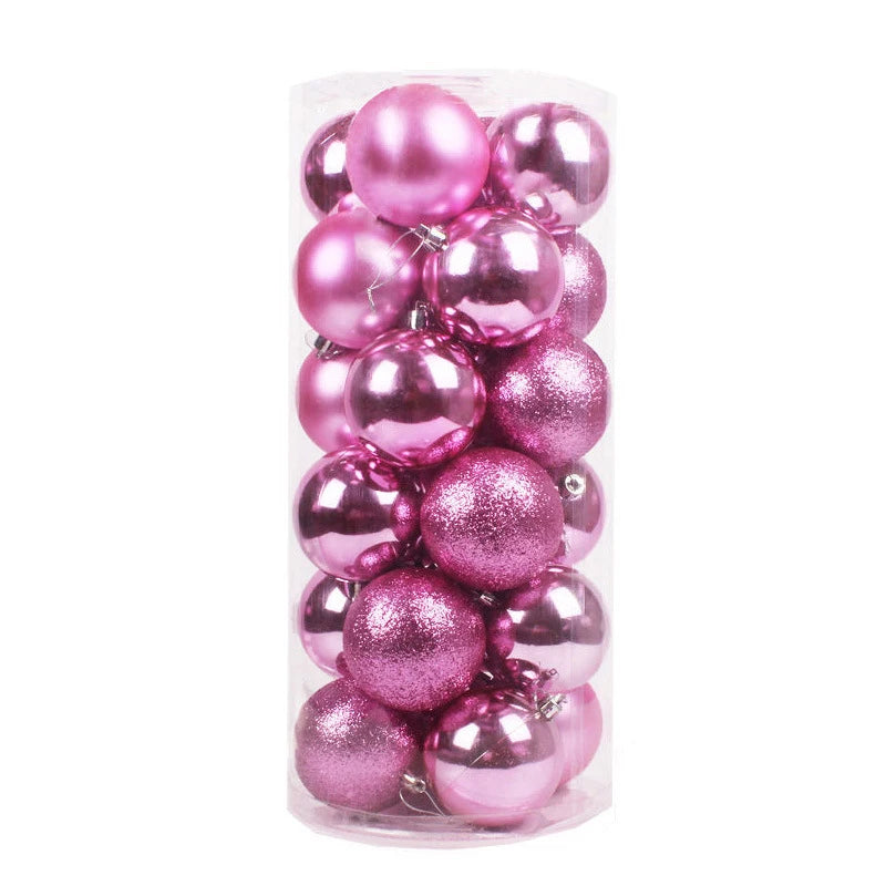 A clear cylindrical container filled with pink Christmas baubles, some matte, some shiny, and some glittery.