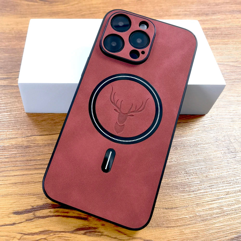 A smartphone with a red-brown case featuring a deer emblem. The case has a circular design and cutouts for three camera lenses. The phone rests on a white box on a wooden surface.