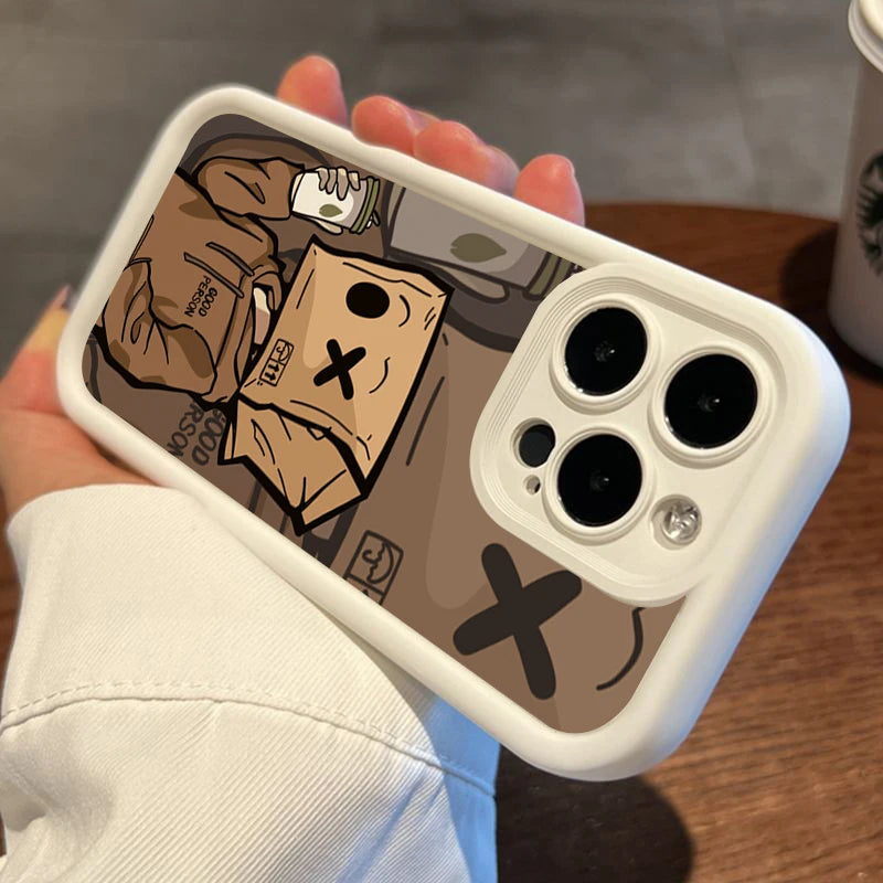 Person holding an iPhone with a white case featuring a cartoon of someone with a drink and a paper bag marked with an 'X.' Background includes a coffee cup on a wooden table.