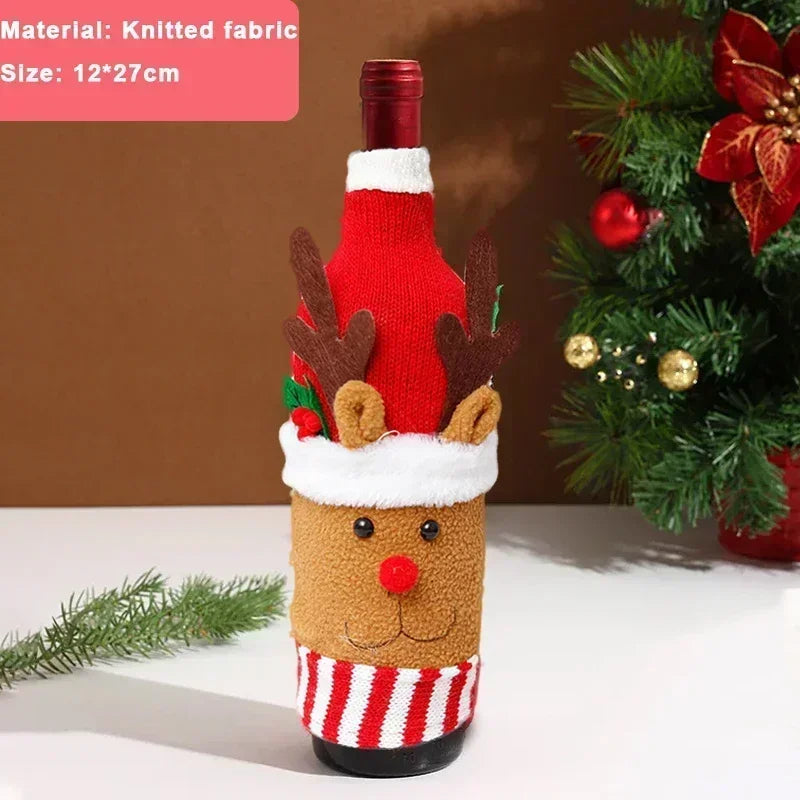 Festive wine bottle dressed in a reindeer knit cover with antlers and a red nose, next to a decorated Christmas tree branch.