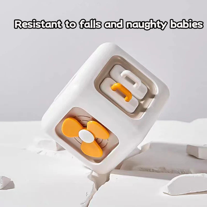 A white cube toy with interactive orange elements rests on a cracked surface. Text above reads, "Resistant to falls and naughty babies," highlighting its durability.