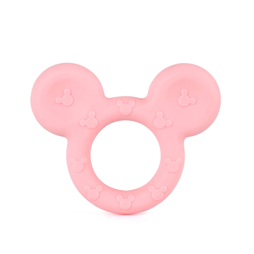 Pink silicone teething toy with a circular center and two rounded ears, featuring embossed designs. The shape resembles a stylized animal face or character icon.