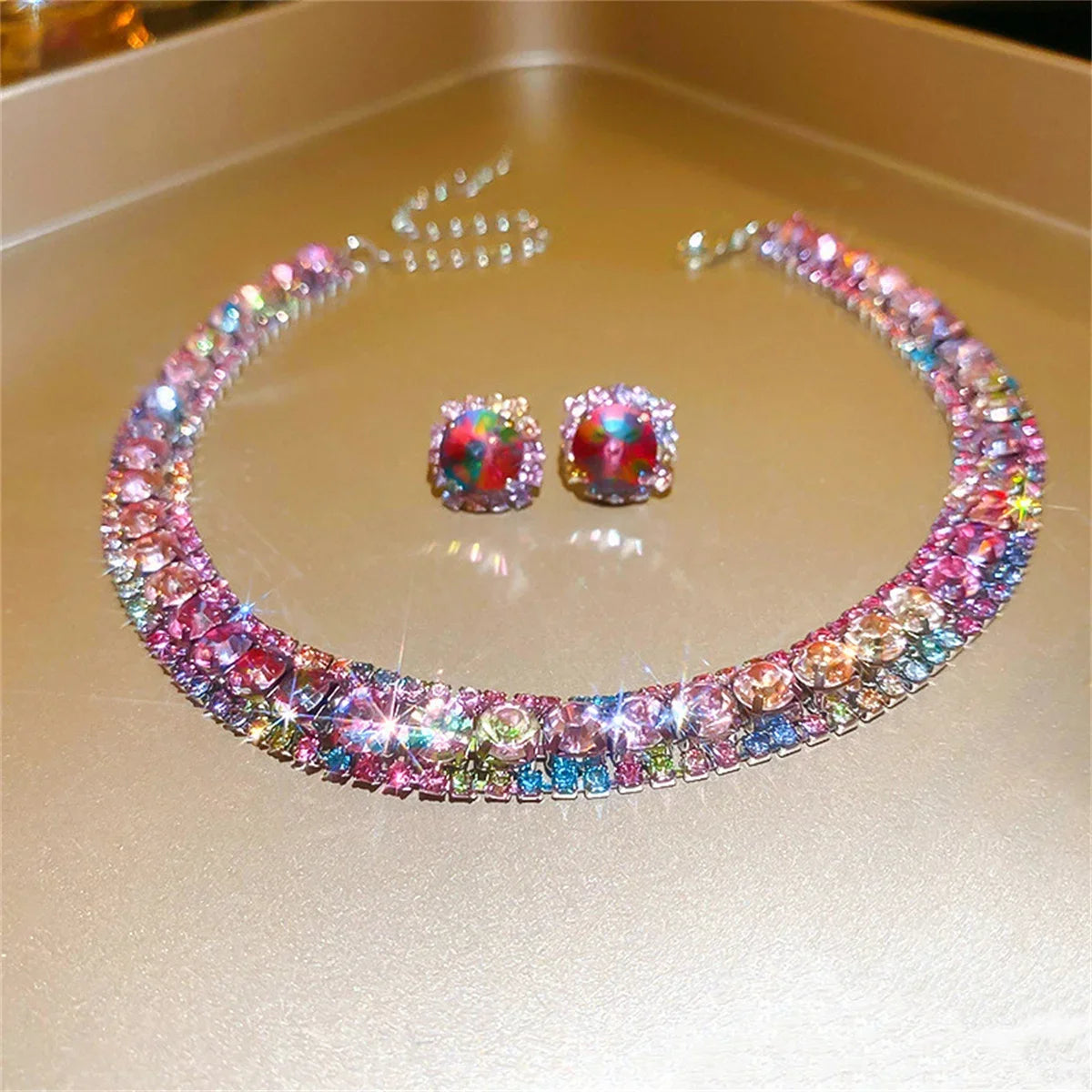 Colorful rhinestone necklace with matching earrings on a gold surface, emitting sparkle and reflections, creating a vibrant and luxurious display.