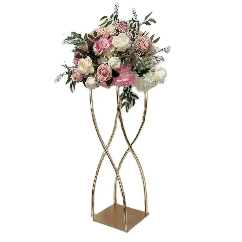 Elegant bouquet of pink and white flowers with greenery on a gold twisted metal stand, set against a plain white background.