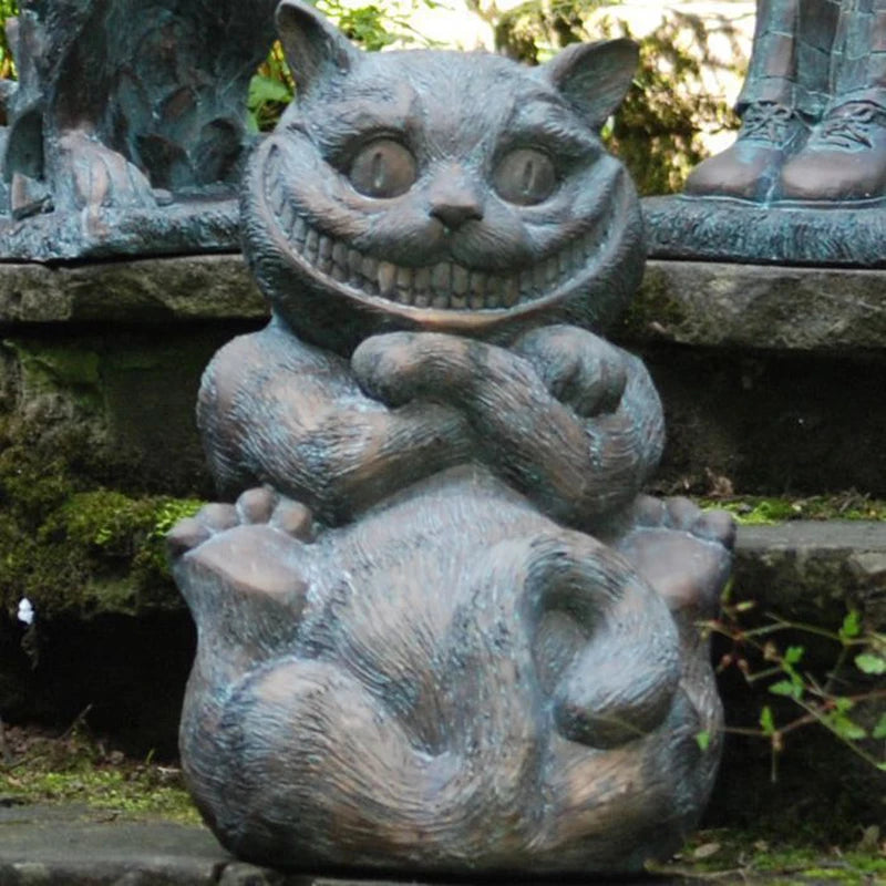 Stone sculpture of a grinning Cheshire Cat with cross-legged posture and detailed fur, set against a mossy stone background, next to some human-like feet.