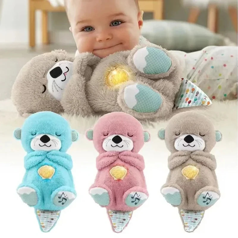 A baby cuddles a plush otter toy with a glowing light on its belly. Below are three similar stuffed otters in blue, pink, and brown with musical notes on their feet.