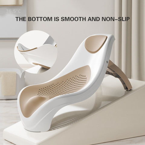 A modern, ergonomic baby bath seat with a smooth, non-slip bottom. The white and beige design includes a perforated seat for drainage, set against a minimalistic bathroom background.