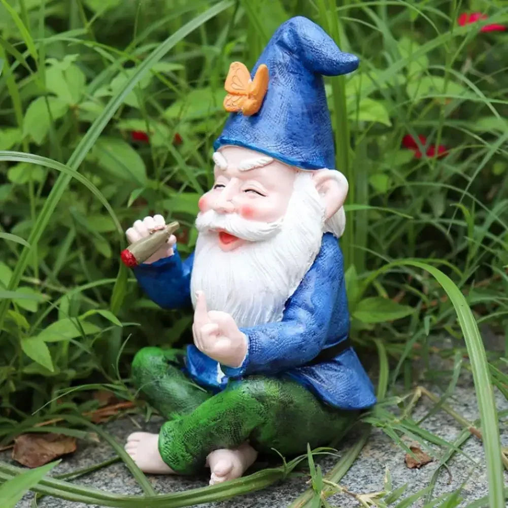 A garden gnome with a white beard and blue hat sits among green plants, holding a miniature pipe with a red tip, wearing a blue coat and green pants, smiling with eyes closed.