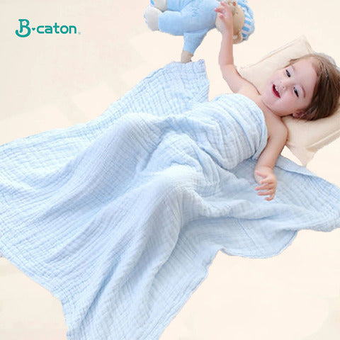 A child lies on a bed, smiling and reaching up, covered by a light blue blanket. A stuffed animal is at their side. The brand name "B-caton" is visible in the corner.