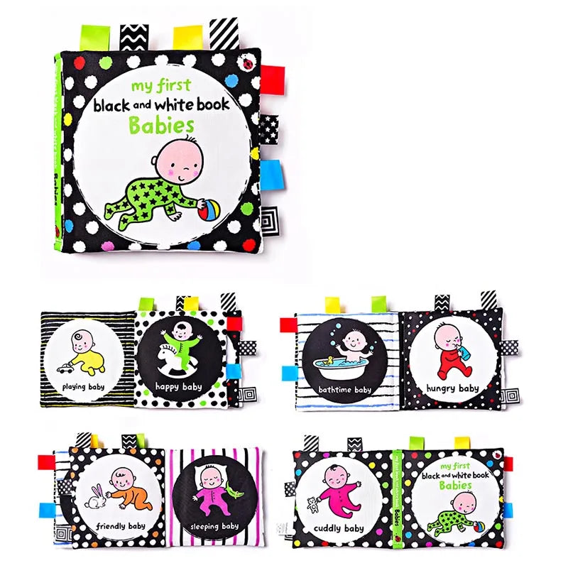 Colorful cloth baby book titled "My First Black and White Book: Babies" features playful images of babies with activities like playing, smiling, bathing, and sleeping, decorated with tabs.