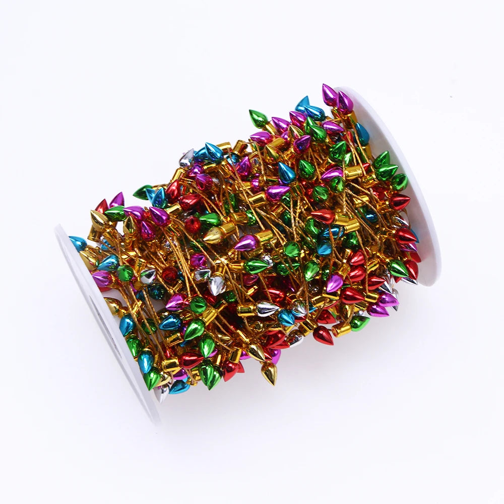 Spool of shiny, multicolored decorative beads on golden wire, featuring red, green, blue, purple, and silver teardrop shapes.