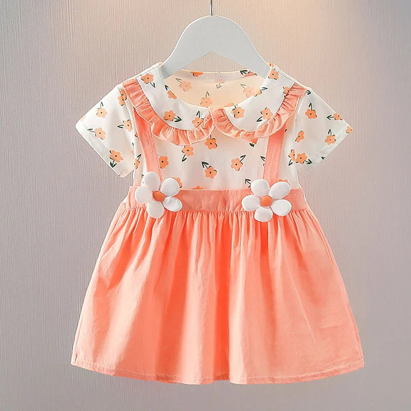 Peach dress with floral-print top and white daisies on straps, displayed on a hanger. Short sleeves and a Peter Pan collar add a sweet touch to this playful outfit.