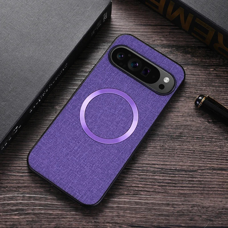 Purple fabric-textured smartphone case with a metallic circular ring, placed on a wooden surface next to a pen and closed books.