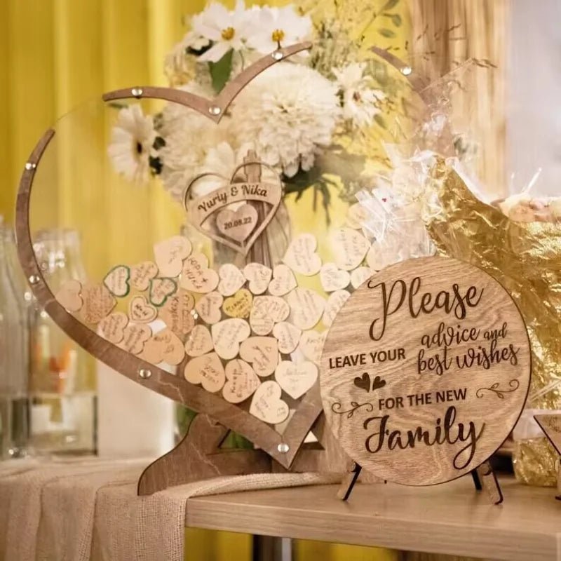 Wooden heart guestbook with small heart messages beside a circular sign inviting advice for the new family. Flowers and a gold decoration adorn the background.