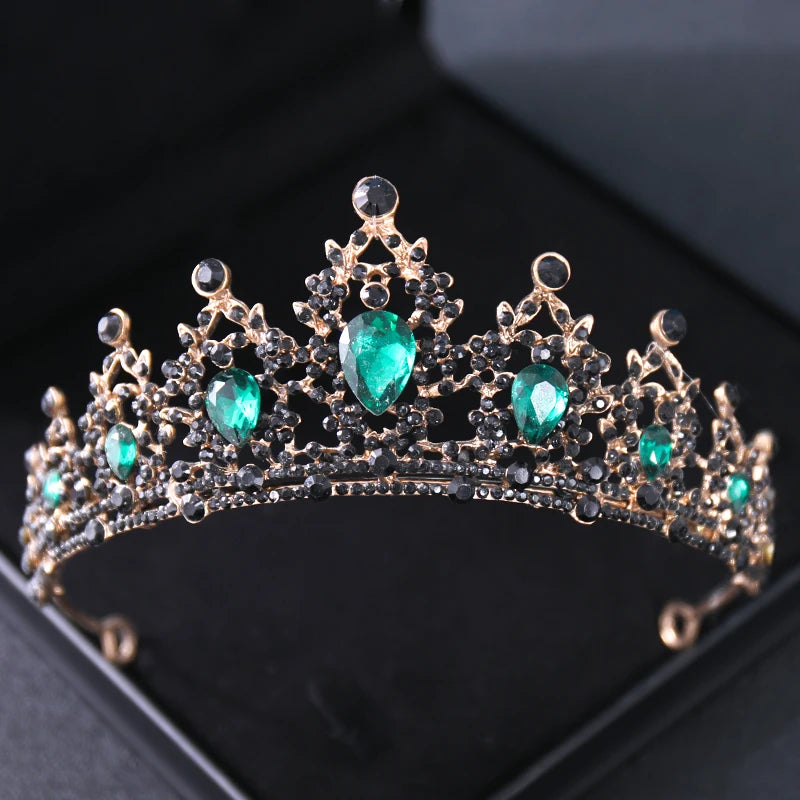 Gold tiara adorned with pear-shaped green gemstones and black crystals, set against a dark background. The elegant design features intricate detailing and symmetrical patterns.