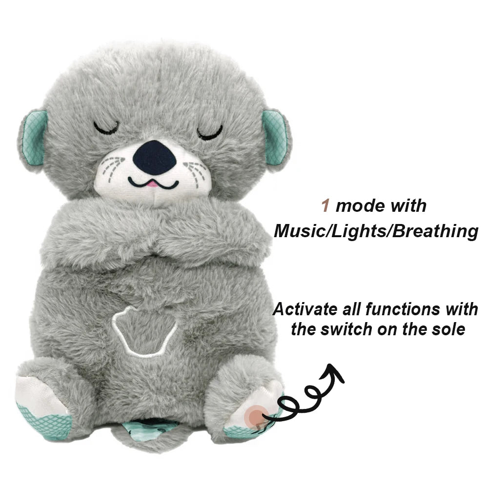 A gray plush otter with closed eyes and teal accents offers music, lights, and breathing effects. Features a paw design and can be activated with a sole switch.