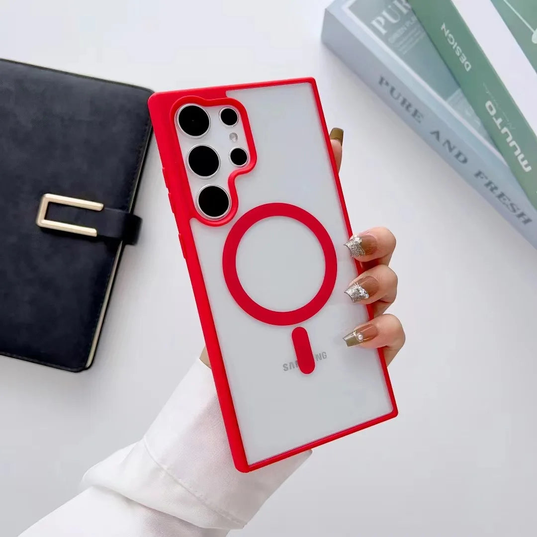 Person holding a Samsung phone with a red magnetic case featuring a prominent circular design. A black planner and books are visible in the background.
