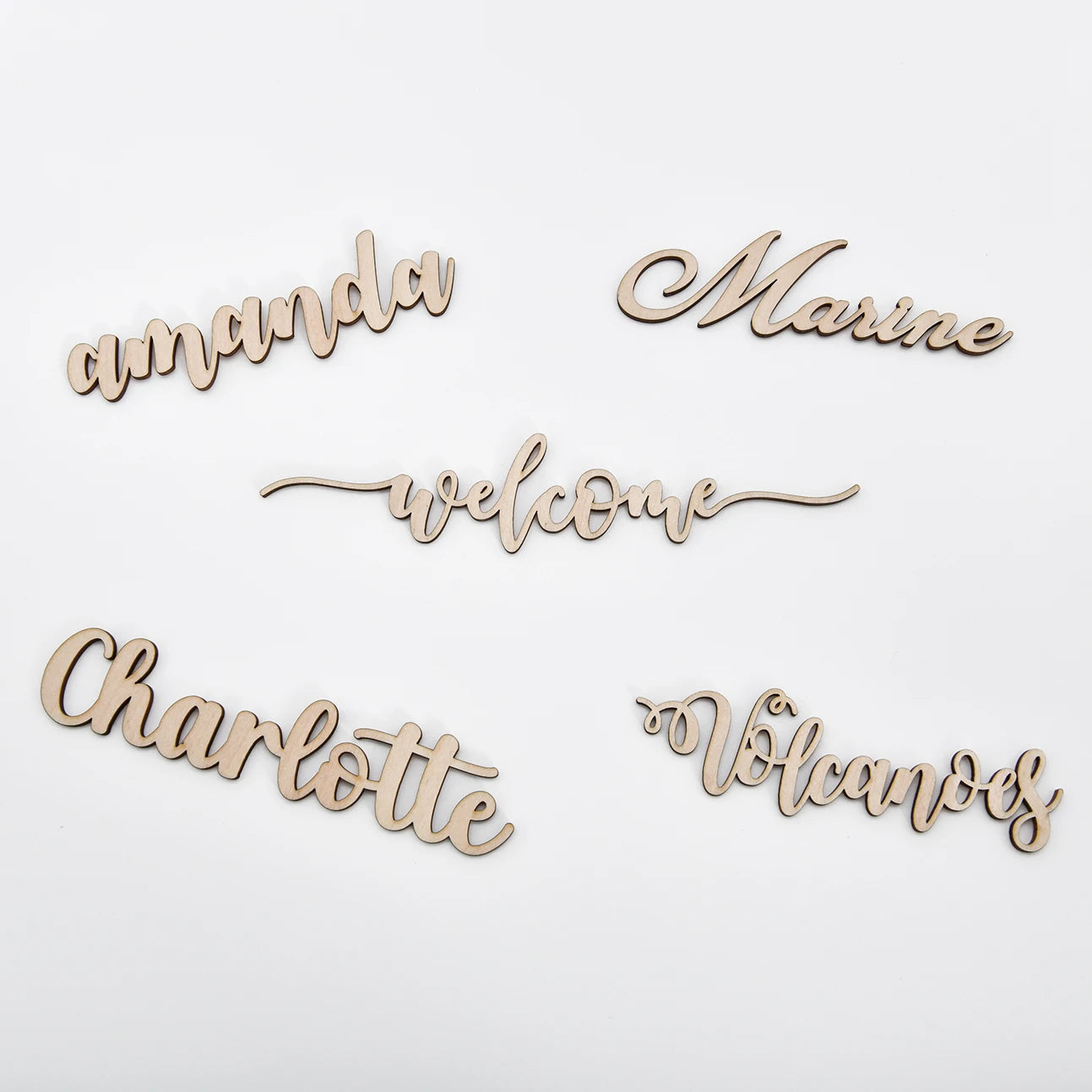 Wooden cutouts of names "amanda," "Marine," "Charlotte," and "Volcanoes," plus "welcome," arranged on a white background in cursive script.